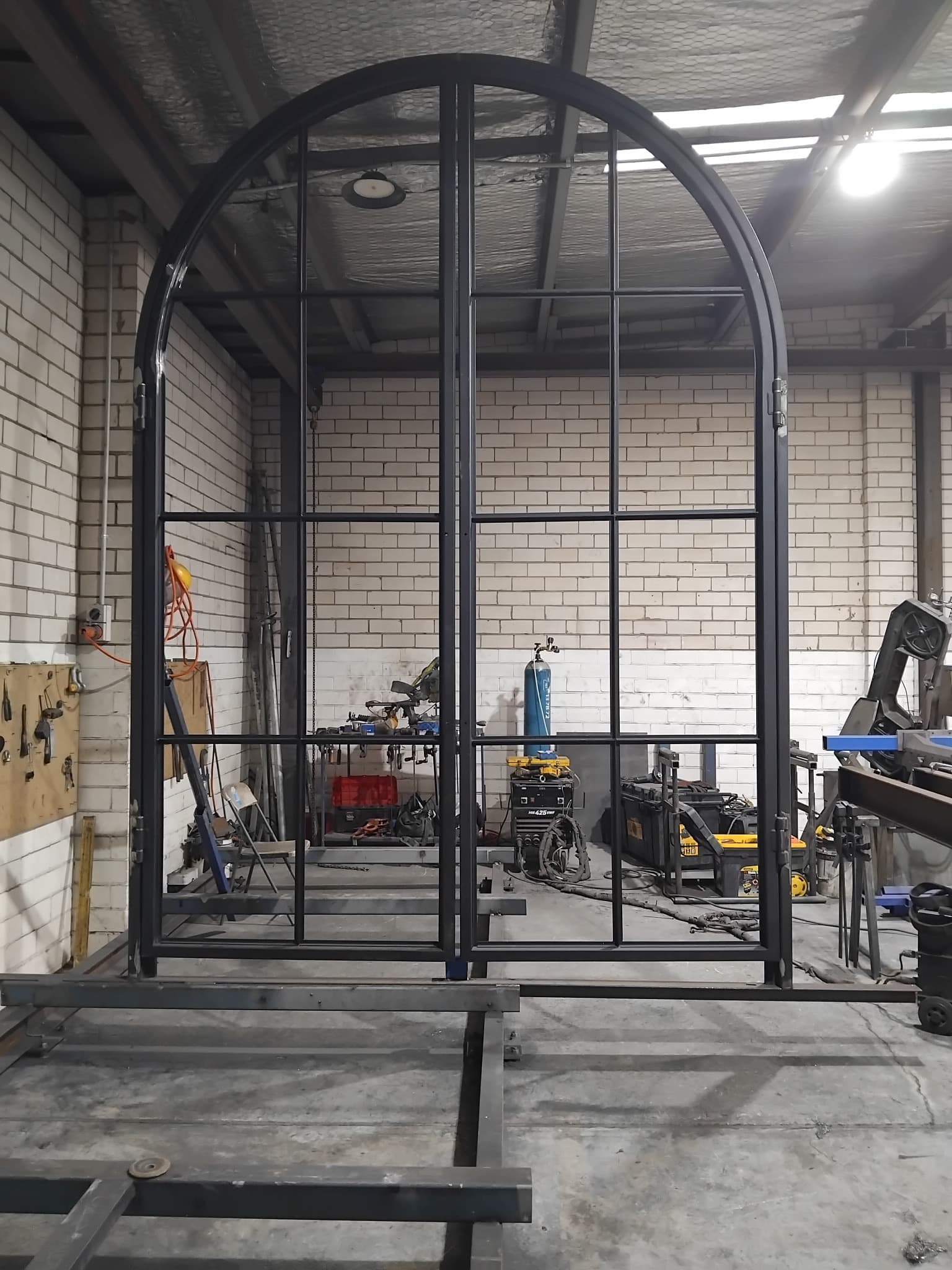 Arched black steel frame being assembled in a workshop